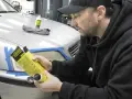 Man förbereder polering strålkastare biltema. En flaska med produkt och trasa ligger på bilen.