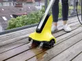 En person använder en Kärcher borste för att rengöra en träaltan.