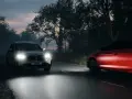 Två bilar kör på en mörk väg. Den ena är silverfärgad med starka H7 LED e-godkänd strålkastare. Den andra är röd och suddig av rörelse.