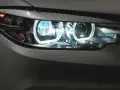 Detaljerad bild av en BMW-bil med tända auto ljus. De blåvita LED-lamporna lyser starkt.