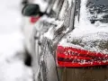En mörk bil täckt av snö och is. En perfekt dag för ett bilvårdspaket för att få bilen skinande ren igen.