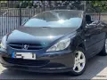 Svart Peugeot 307 CC cabriolet, taket nere. Solen reflekteras i lacken, kanske ett tecken på ett kommande problem?