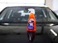 En flaska SONAX Xtreme Wet Coat står på en våt, mörk bilhuv.
