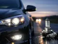 Bilens strålkastare lyser starkt i skymningen. Bredvid bilen ligger nya H7 LED-lampor, redo att ge klarare sikt på vägen.