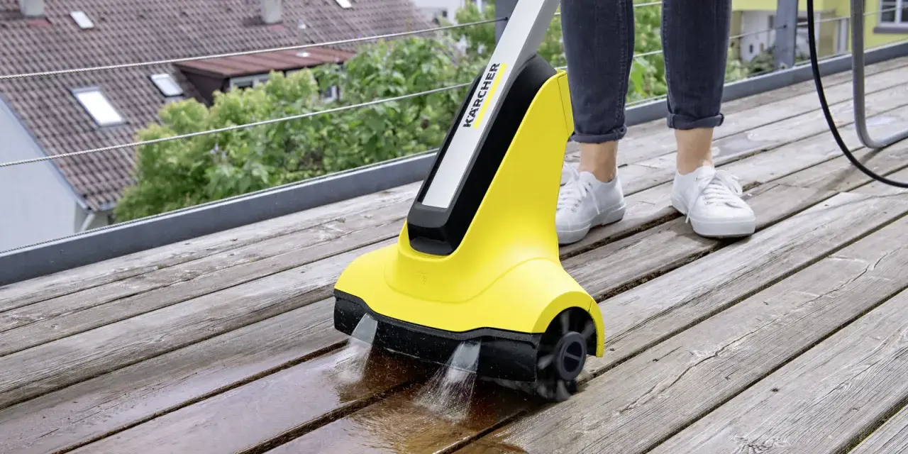 En person använder en Kärcher borste för att rengöra en träaltan.