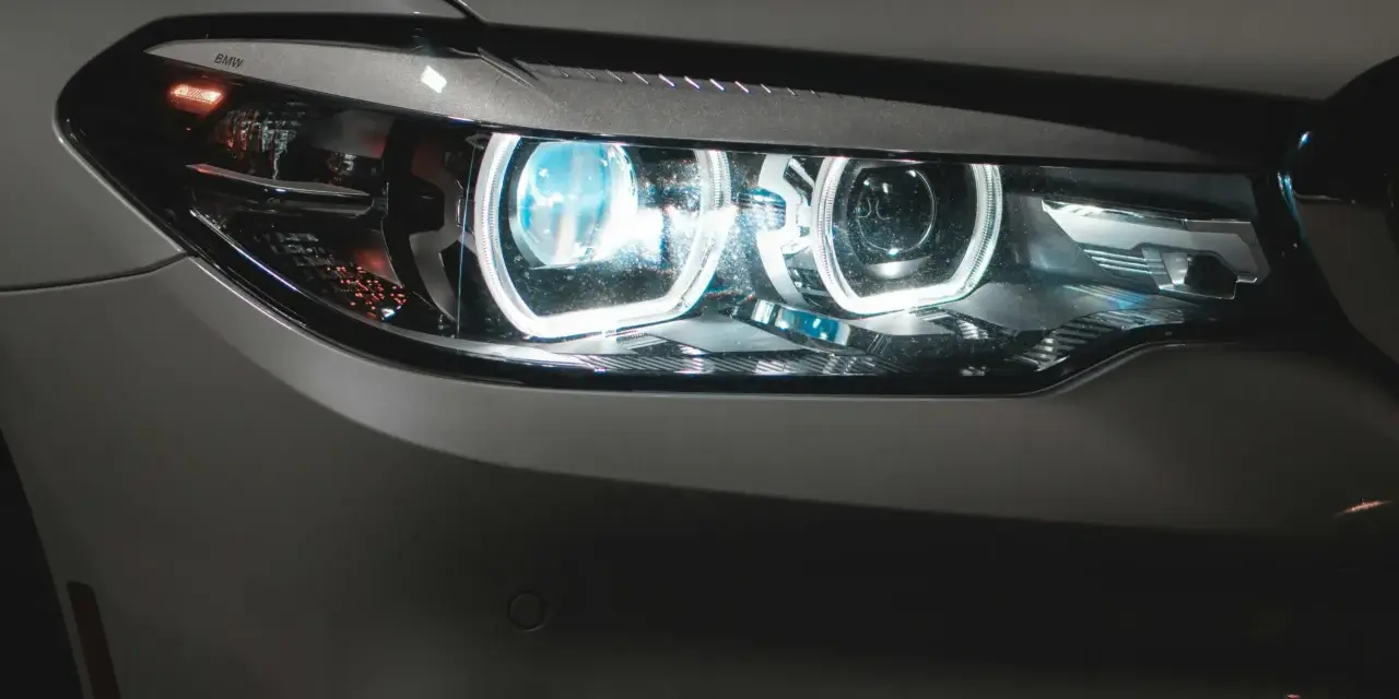 Detaljerad bild av en BMW-bil med tända auto ljus. De blåvita LED-lamporna lyser starkt.