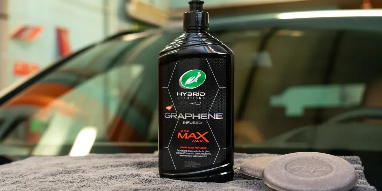 En flaska Turtle Wax Hybrid Solutions Pro Graphene Infused Wax, ett bilschampo för maximal glans och skydd, ligger på en grå handduk.