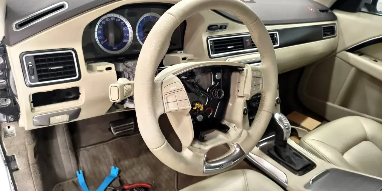 Interiör av en Volvo S80 där instrumentpanelen är demonterad, troligen på grund av ett volvo s80 problem. Ratt och mittkonsol syns.