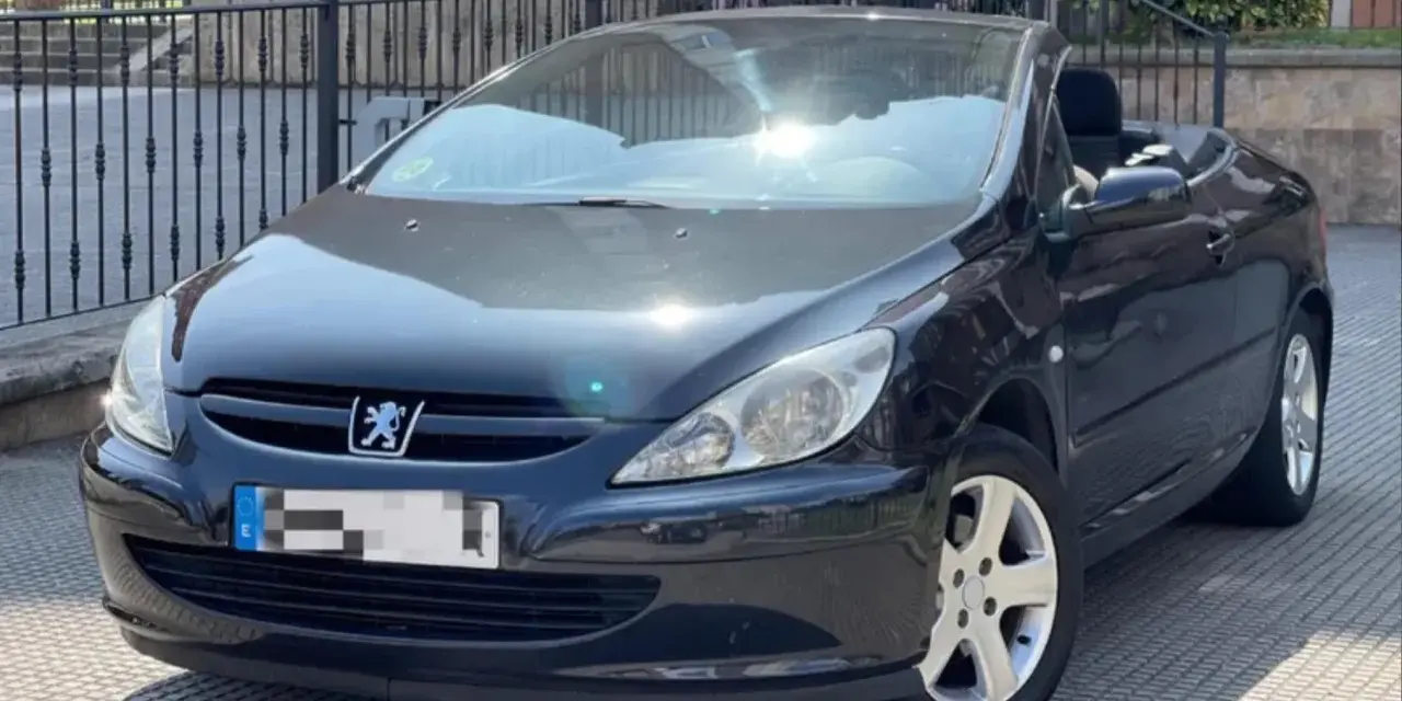 Svart Peugeot 307 CC cabriolet, taket nere. Solen reflekteras i lacken, kanske ett tecken på ett kommande problem?