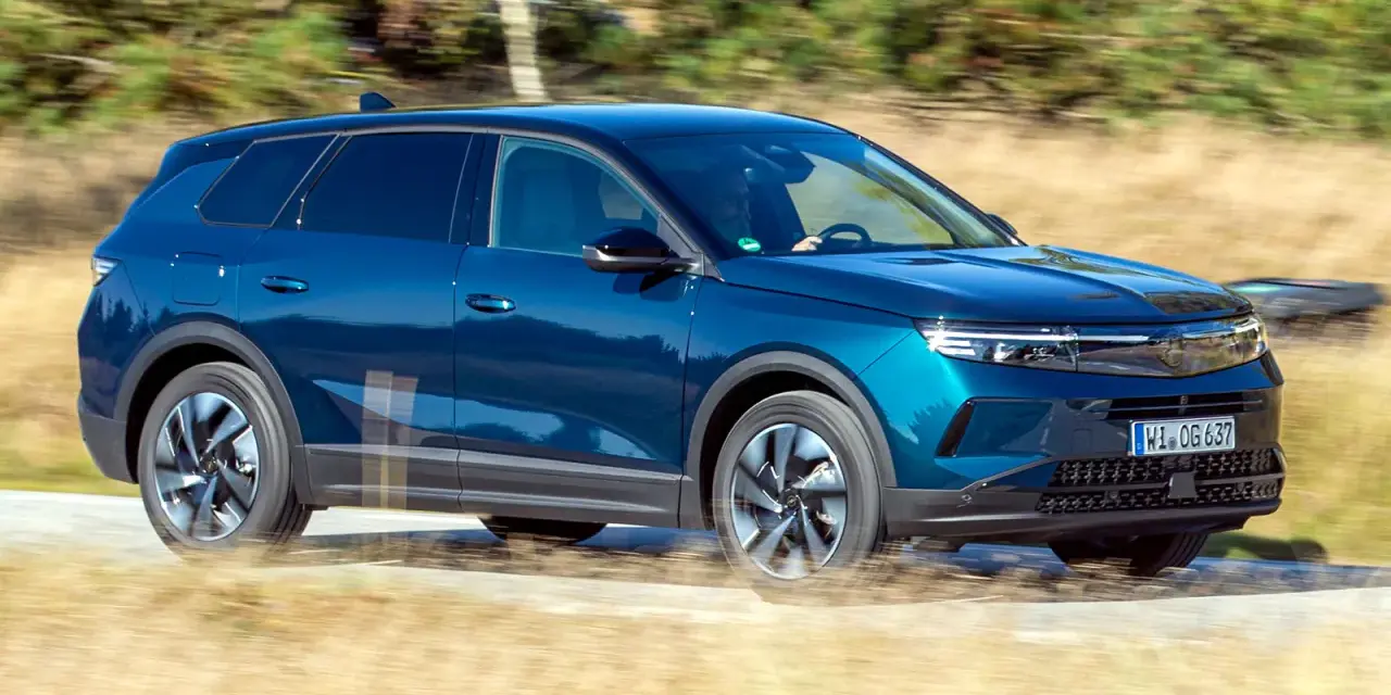 Blå Opel Grandland kör på en grusväg, kanske med ett litet **opel grandland problem** med dammet som virvlar upp.