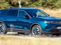 Blå Opel Grandland kör på en grusväg, kanske med ett litet **opel grandland problem** med dammet som virvlar upp.