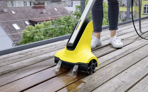 En person använder en Kärcher borste för att rengöra en träaltan.
