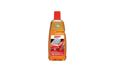 En flaska Sonax Car Wash Shampoo Concentrate, en orange vätska med röd kork. Perfekt för att skapa mycket skum vid biltvätt.