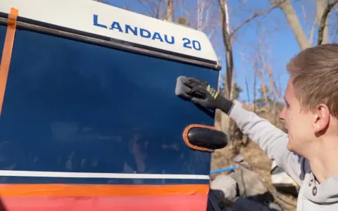 Man applicerar keramisk lackskyddsbehandling på en blå båt med texten "LANDAU 20".