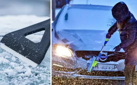 En person med huva skrapar rutan på en Volvo i snöstorm. En isskrapa ligger på isig mark.