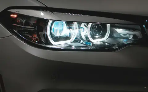 Detaljerad bild av en BMW-bil med tända auto ljus. De blåvita LED-lamporna lyser starkt.