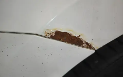 Rostfläckar på vit bil, dags att slipa rost innan det blir värre.
