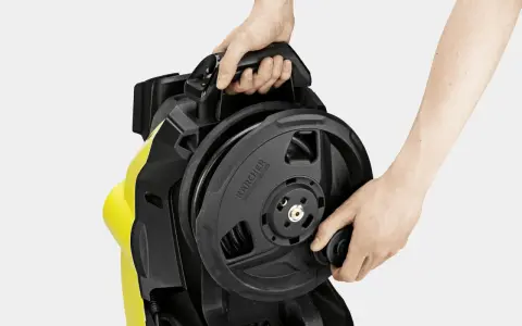 Händerna rullar in slangen på en Kärcher K7 Premium högtryckstvätt.