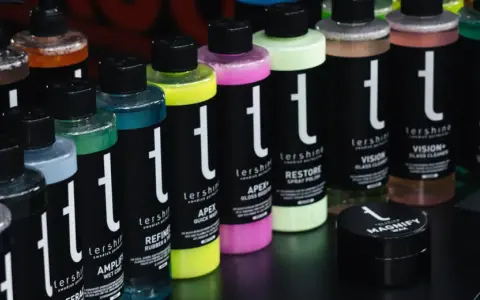 Rader av färggranna flaskor med bilvårdsprodukter, inklusive sprayflaskor, står uppradade.