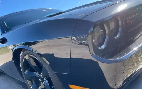 Svart Dodge Challenger med en glans som en ängel, tack vare angelwax. Solen reflekteras i den blanka lacken.