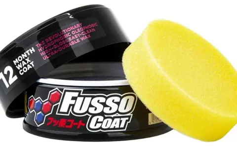 En burk med Fusso Coat 12 Month Wax Coat och en gul applikatorsvamp. Ger en revolutionerande, hydrofobisk och hållbar glans.
