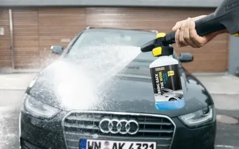 En hand sprutar Kärcher skum på en mörk Audi. Bilen får en djuprengöring med hjälp av Kärcher Ultra Foam Cleaner.