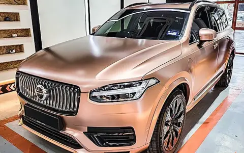 En lyxig Volvo XC90 med en glänsande roséguld folierad bil. Bilen står i ett garage med orange linjer på golvet.
