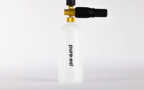 En vit behållare med texten "pure:est" och en skumlanse med mässingsdetaljer.