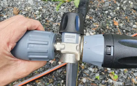 Hand connecting a Kärcher foam lance to a Kärcher K5 pressure washer.