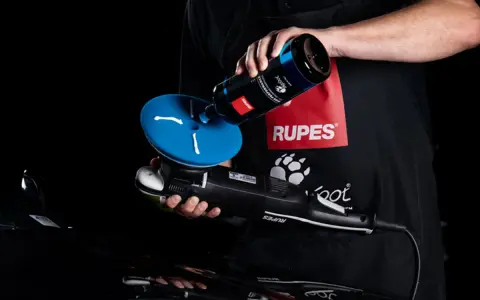 Person applicerar Rupes da coarse polermedel på en polertrissa.