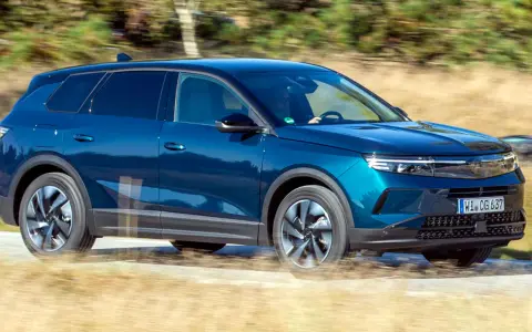 Blå Opel Grandland kör på en grusväg, kanske med ett litet **opel grandland problem** med dammet som virvlar upp.