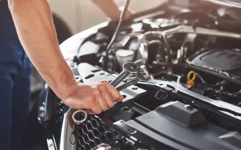 Mekaniker håller verktyg nära motorn på en Renault Megane, redo för kamremsbyte.