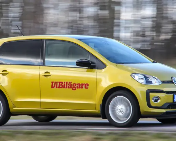 Gul Volkswagen up! kör på en väg. Texten "ViBilägare" syns på sidan. Ett potentiellt vw up problem kan vara dess lilla storlek.