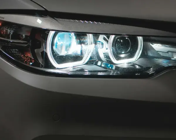 Detaljerad bild av en BMW-bil med tända auto ljus. De blåvita LED-lamporna lyser starkt.
