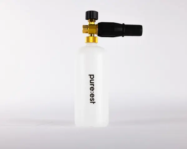 En vit behållare med texten "pure:est" och en skumlanse med mässingsdetaljer.