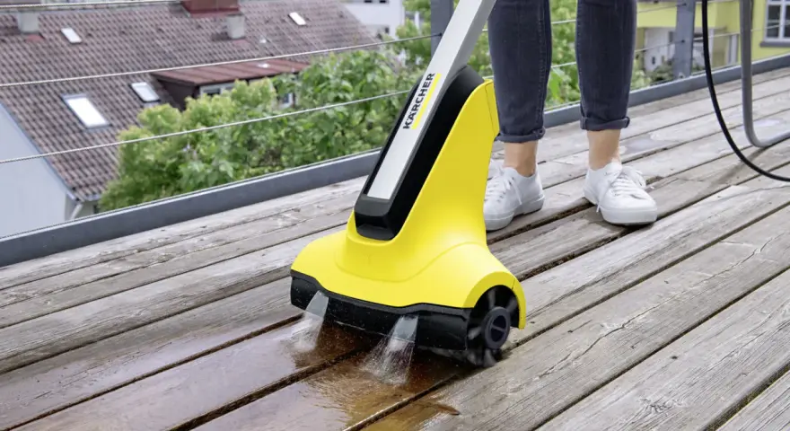 En person använder en Kärcher borste för att rengöra en träaltan.