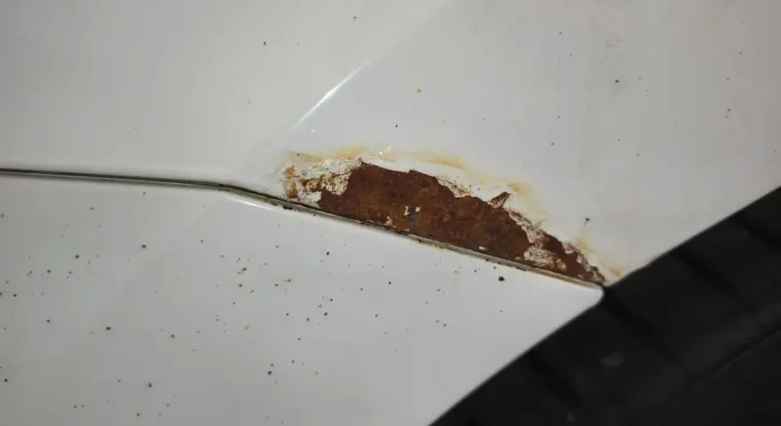 Rostfläckar på vit bil, dags att slipa rost innan det blir värre.