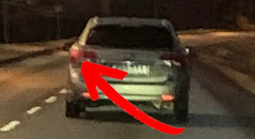 En röd pil pekar på bakljuset på en bil. Det är mörkt ute, och man undrar om man måste ha bakljus på dagen.