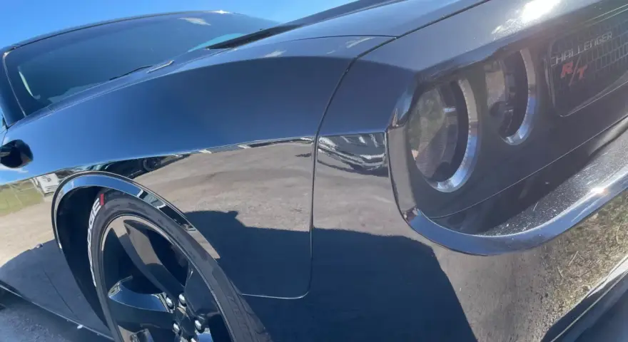 Svart Dodge Challenger med en glans som en ängel, tack vare angelwax. Solen reflekteras i den blanka lacken.
