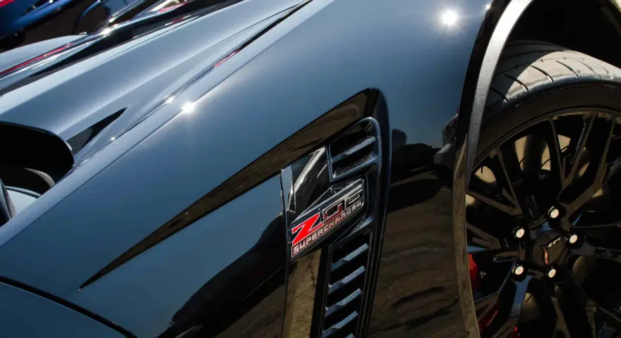 Svart Corvette med "Z06 SUPERCHARGED"-emblem. Lacken är så blank att den nästan ser ut som en keramisk detaljer.