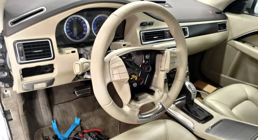 Interiör av en Volvo S80 där instrumentpanelen är demonterad, troligen på grund av ett volvo s80 problem. Ratt och mittkonsol syns.