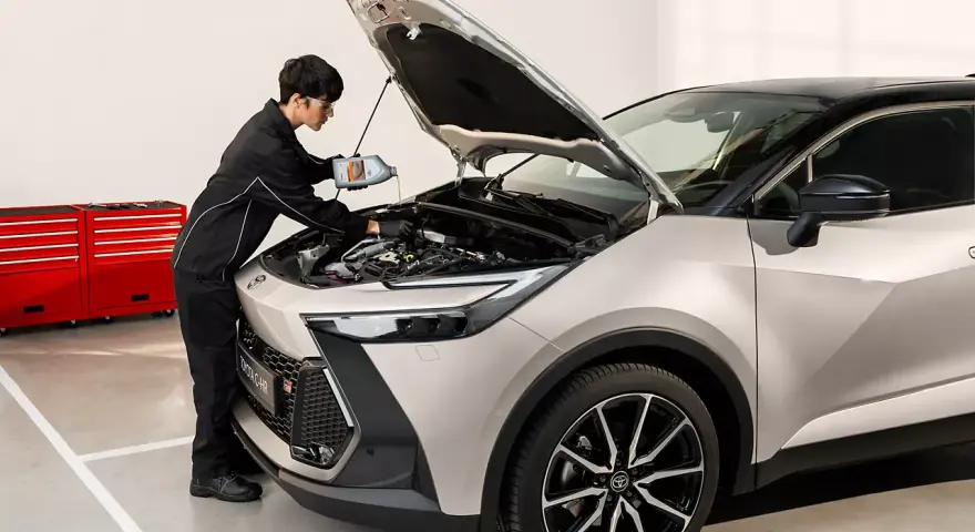 Mekaniker fyller på olja i en Toyota C-HR. För bästa service och pris på din Toyota Yaris, besök oss.