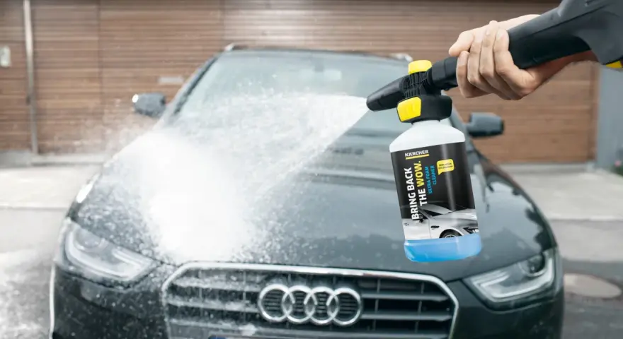 En hand sprutar Kärcher skum på en mörk Audi. Bilen får en djuprengöring med hjälp av Kärcher Ultra Foam Cleaner.