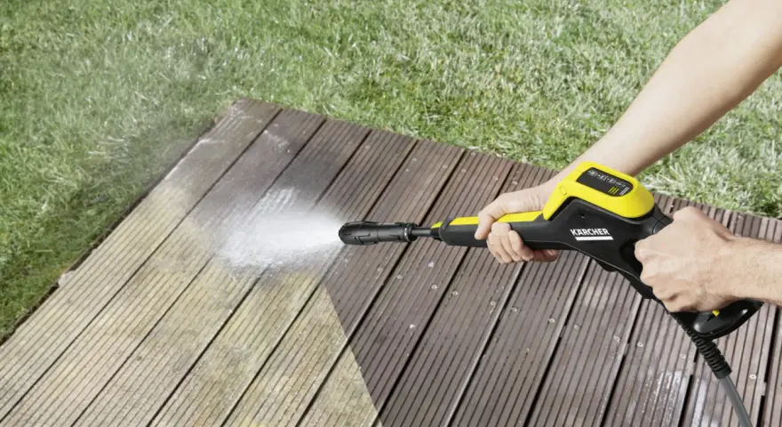 En person använder en Kärcher K4 Power Control för att rengöra en träaltan.