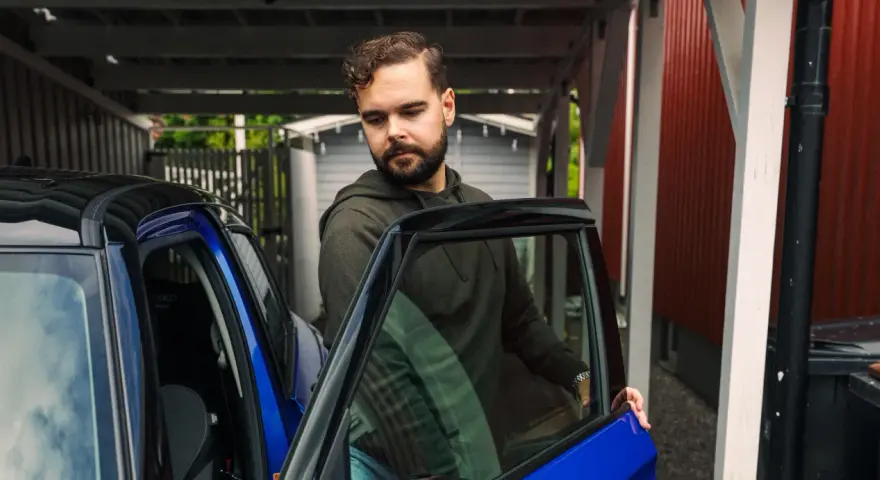 Man öppnar dörren till en blå bil. För att bilen ska hålla sig i gott skick måste man serva bilen varje år.