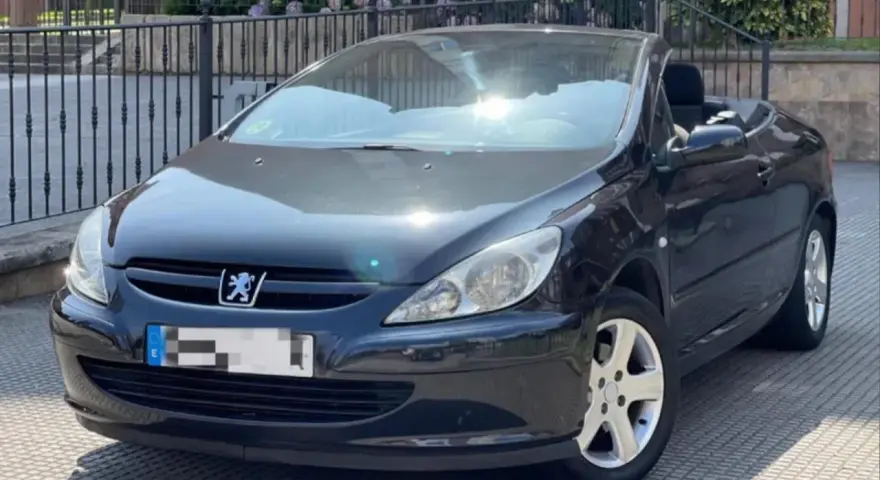 Svart Peugeot 307 CC cabriolet, taket nere. Solen reflekteras i lacken, kanske ett tecken på ett kommande problem?