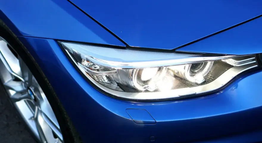 Blå BMW-strålkastare, redo för en prewash. Fälgen syns till vänster.