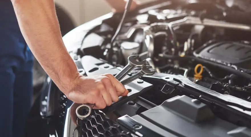 Mekaniker håller verktyg nära motorn på en Renault Megane, redo för kamremsbyte.