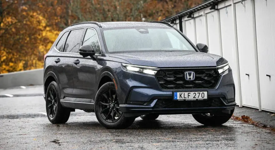 Mörkblå Honda CR-V med svarta fälgar står på en regnvåt asfaltsväg. En potentiell honda cr-v problem kan vara att den drar till sig regn.