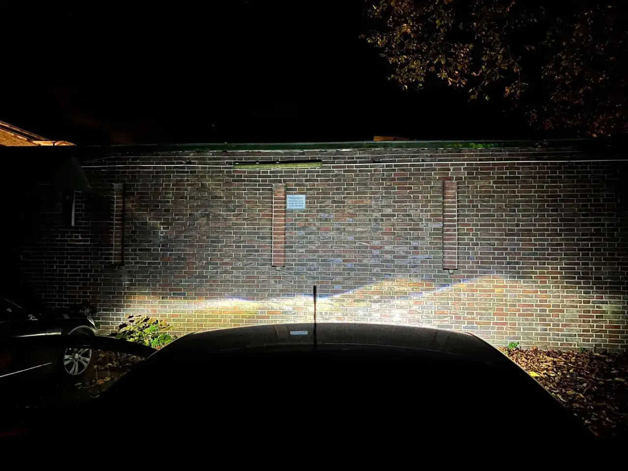 Bilens h7 led-strålkastare lyser upp en tegelvägg i mörkret.